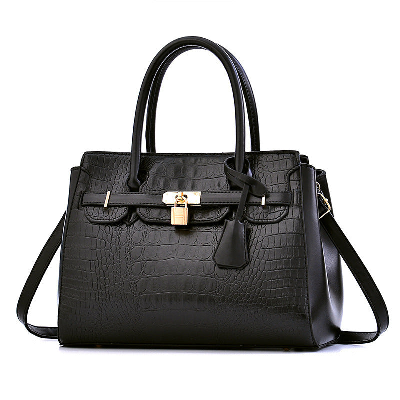 Black crocodile-patterned handbag with a gold lock on a white background