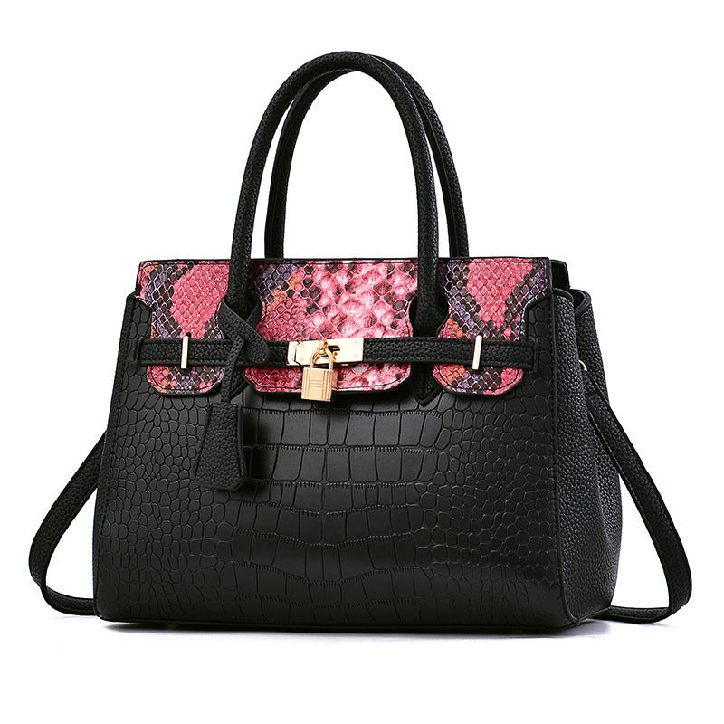 Black handbag with pink and black patterned flap on a white background