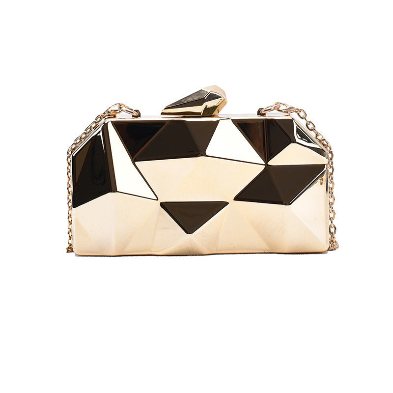 The Prism Aura geometric acrylic clutch shown in gold color. This statement evening bag has a reflective, diamond-cut design and comes with a chain strap.