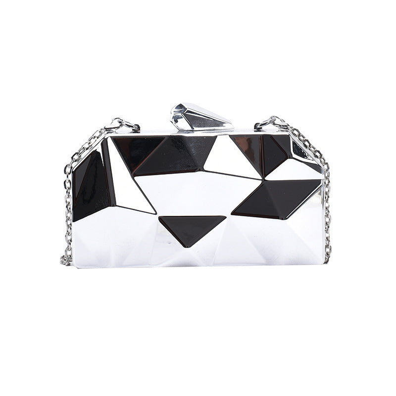 The Prism Aura geometric acrylic clutch shown in silver color. This statement evening bag has a reflective, diamond-cut design and comes with a chain strap.