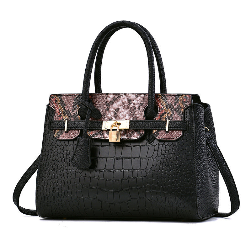 Black handbag with patterned flap and gold lock on a white background