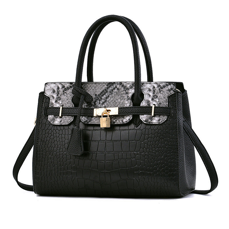 Black handbag with patterned front section on a white background