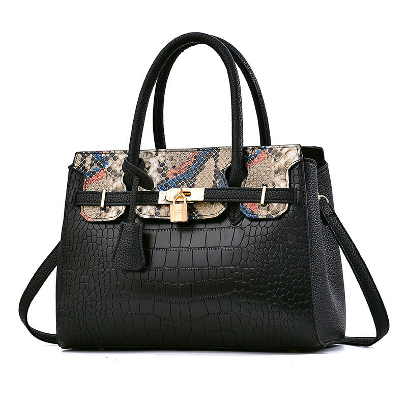 Black handbag with patterned flap and gold clasp on a white background