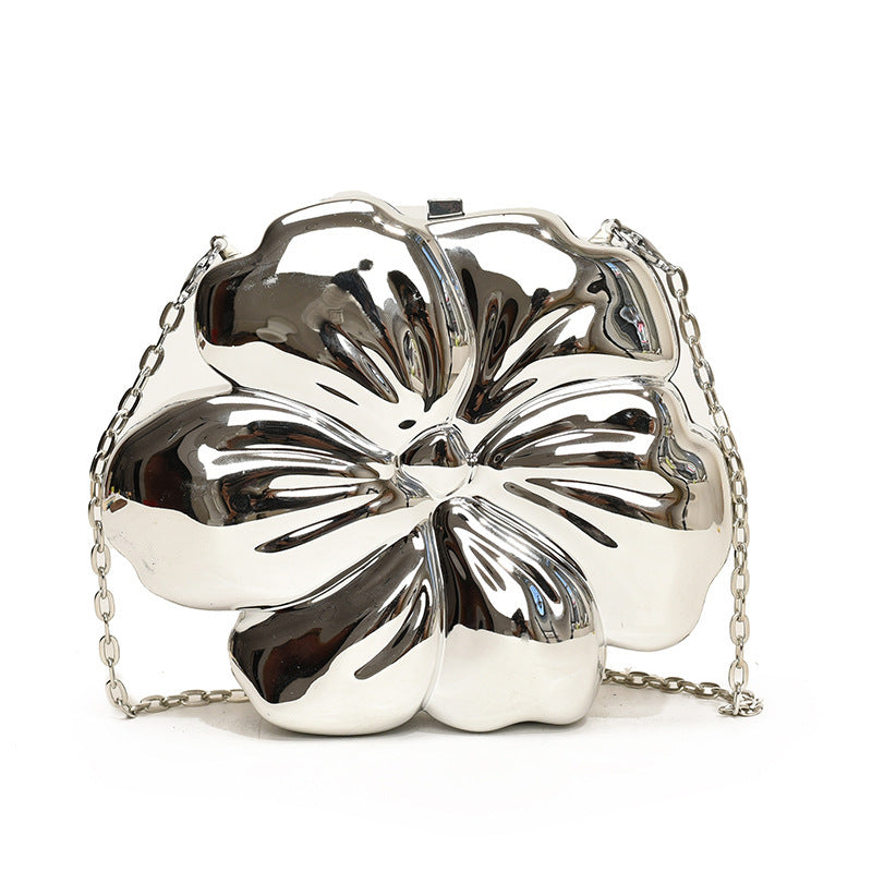 The Baazuu Bloom Bling floral clutch in a metallic silver finish. This sculptural, flower-shaped handbag features a hard-shell design and a chain strap, perfect as a modern statement piece.